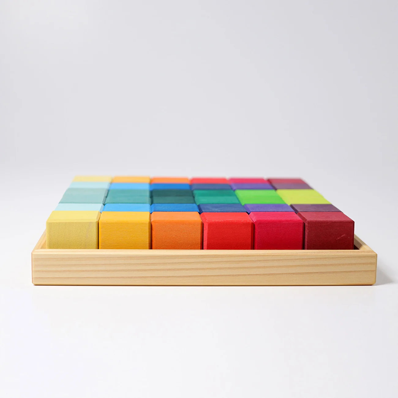 Colorful wooden blocks in a wooden tray on a light gray background