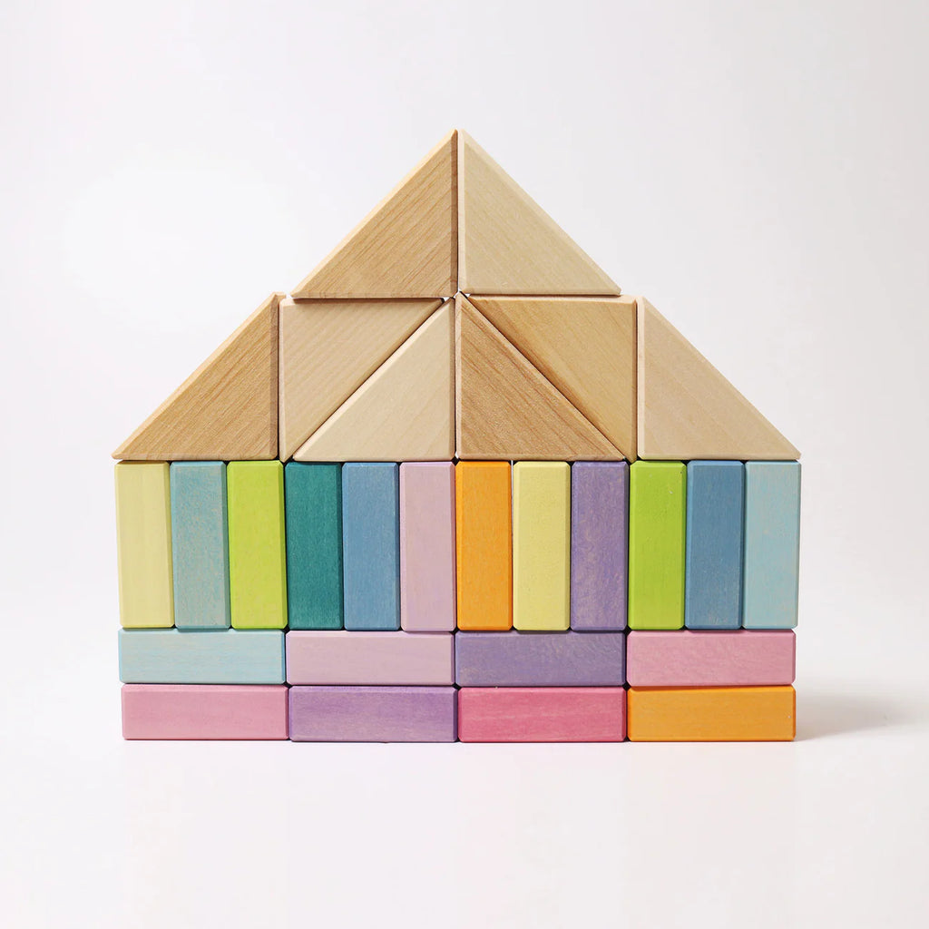 Wooden tangram puzzle shaped like a house with pastel-colored blocks on a white background