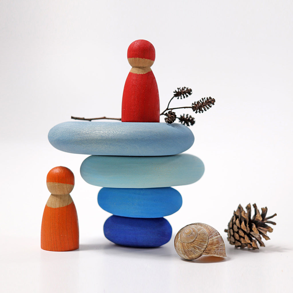 Wooden peg dolls and stacked stones on a white background