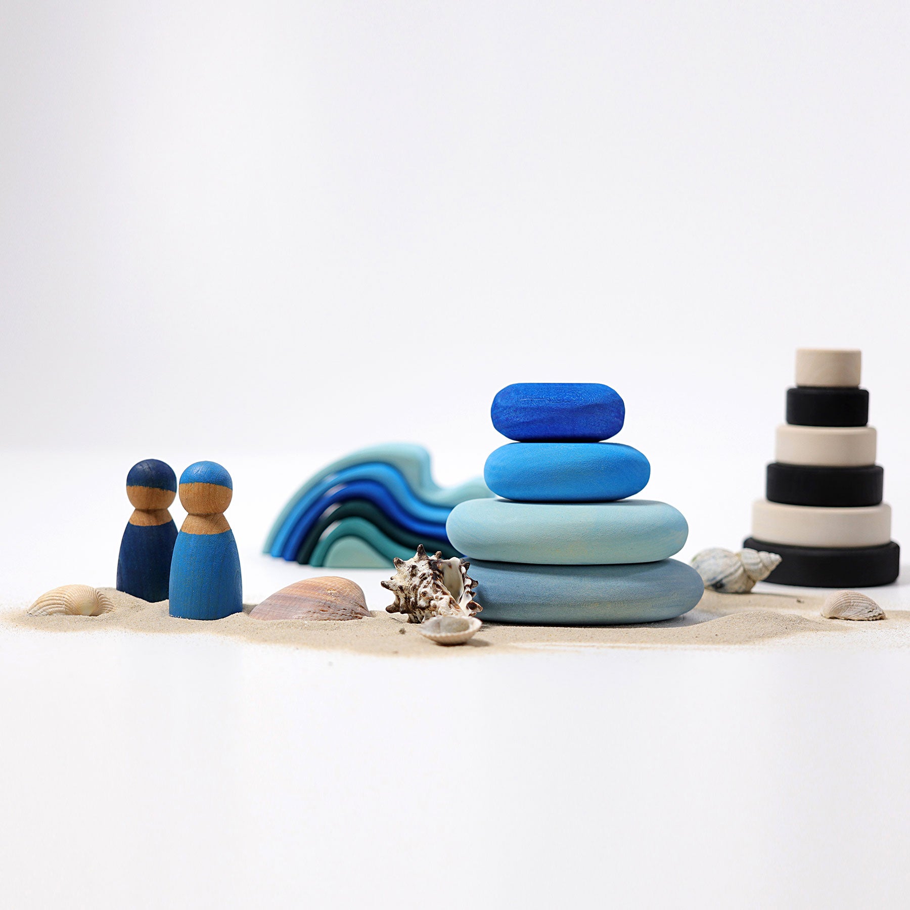 Stacked colorful stones with beach-themed decor on a white background