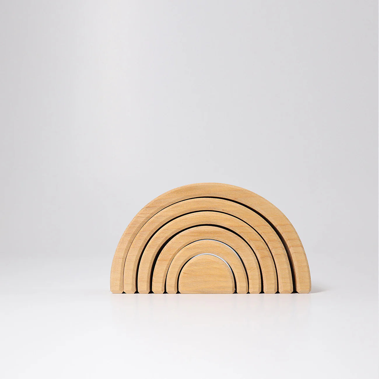 Set of wooden rainbow-shaped building blocks on a light gray background