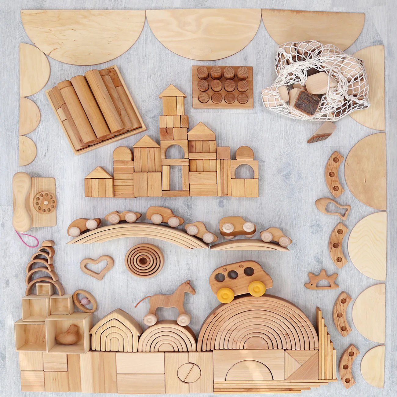 Collection of wooden building blocks and toys on a light gray background