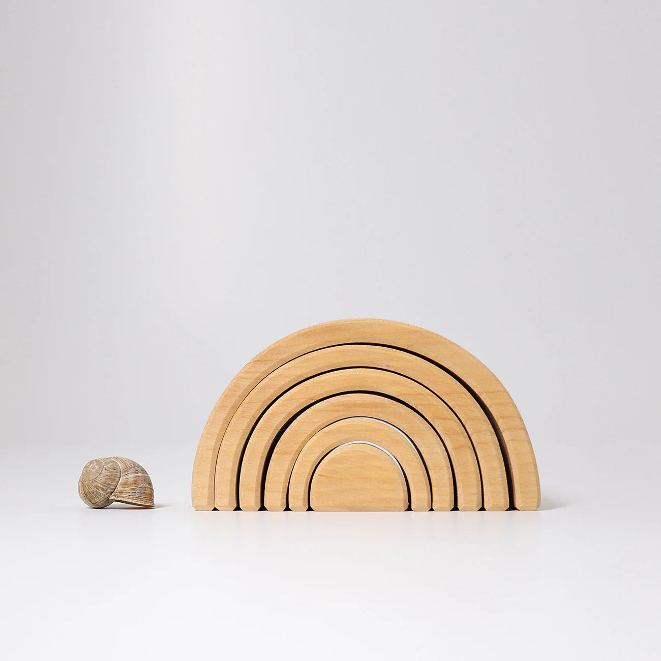 Set of wooden rainbow-shaped building blocks on a light gray background