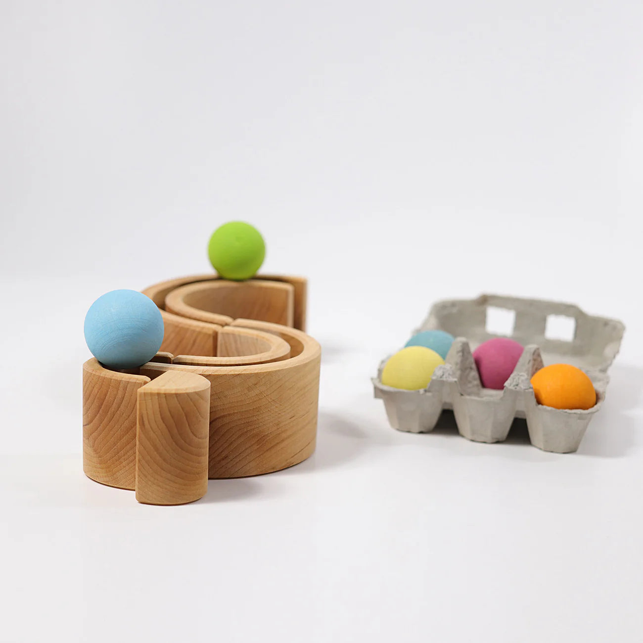Wooden toy track with colorful balls on a white background