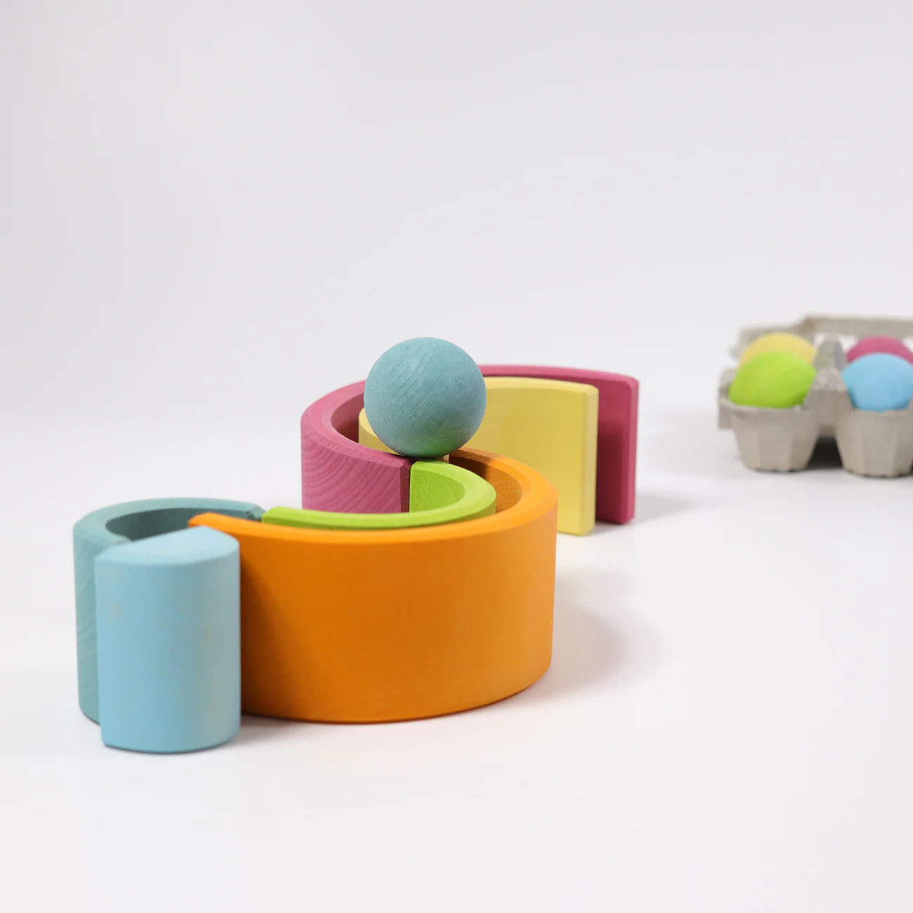 Colorful wooden toy set with cylindrical shapes and a ball on a white background