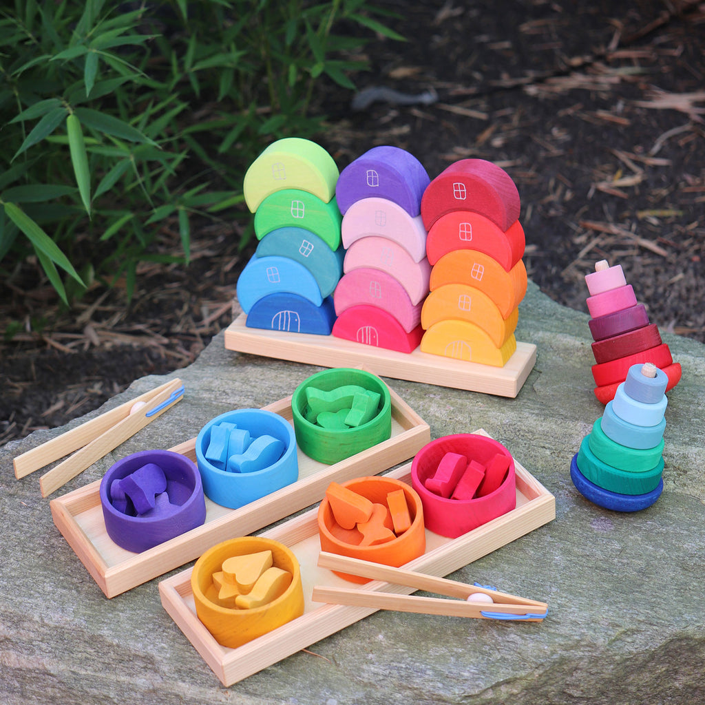 Colorful wooden toys on a stone surface with greenery in the background