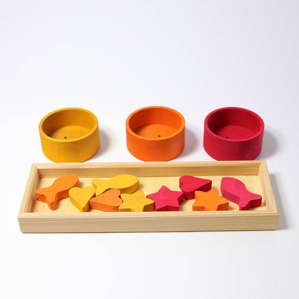 Colorful wooden shape sorting toy with three containers on a white background