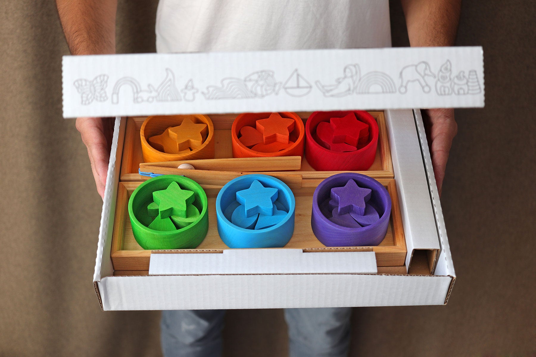 Colorful star-shaped molds in a wooden tray held by a person.