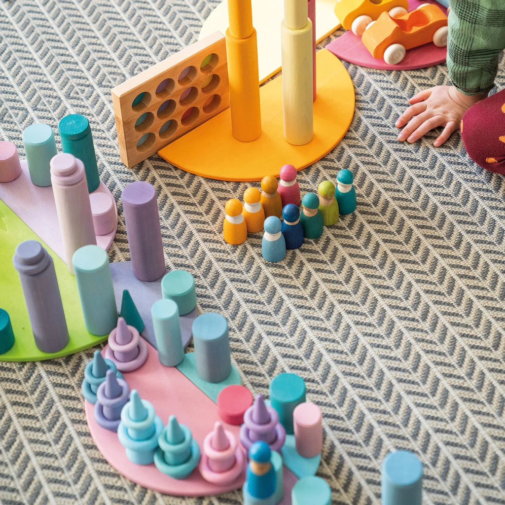 Colorful wooden toys on a textured surface with children's hands interacting.