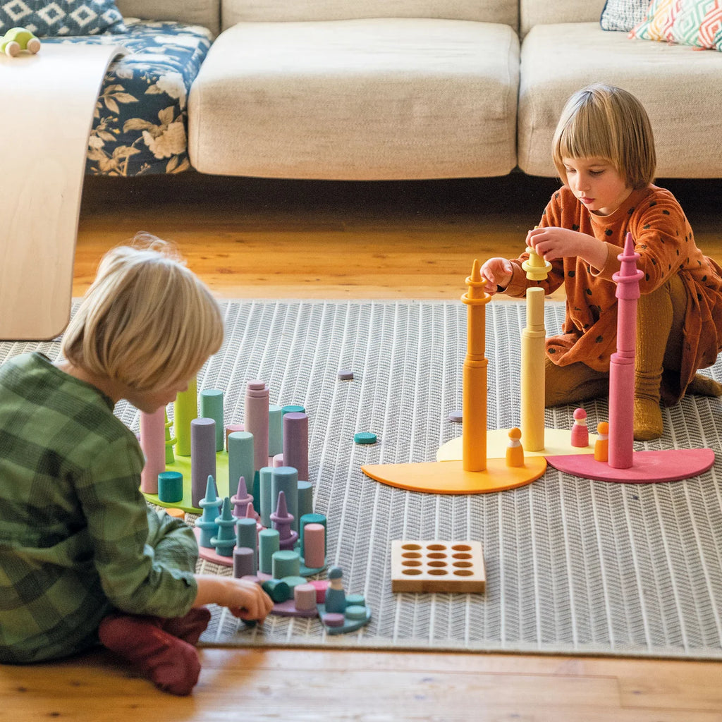 Two children playing with colorful building toys on a rug in a living room.
