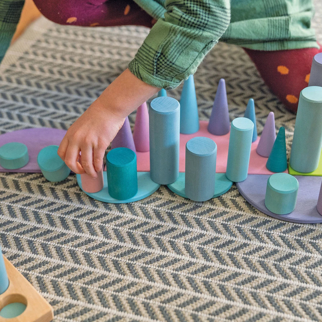 Child playing with colorful geometric shape sorting toy on a patterned rug