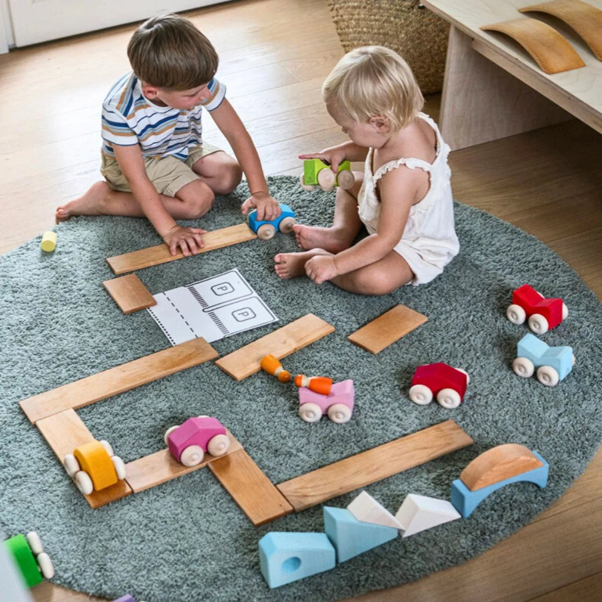 Two children playing with wooden toys on a rug