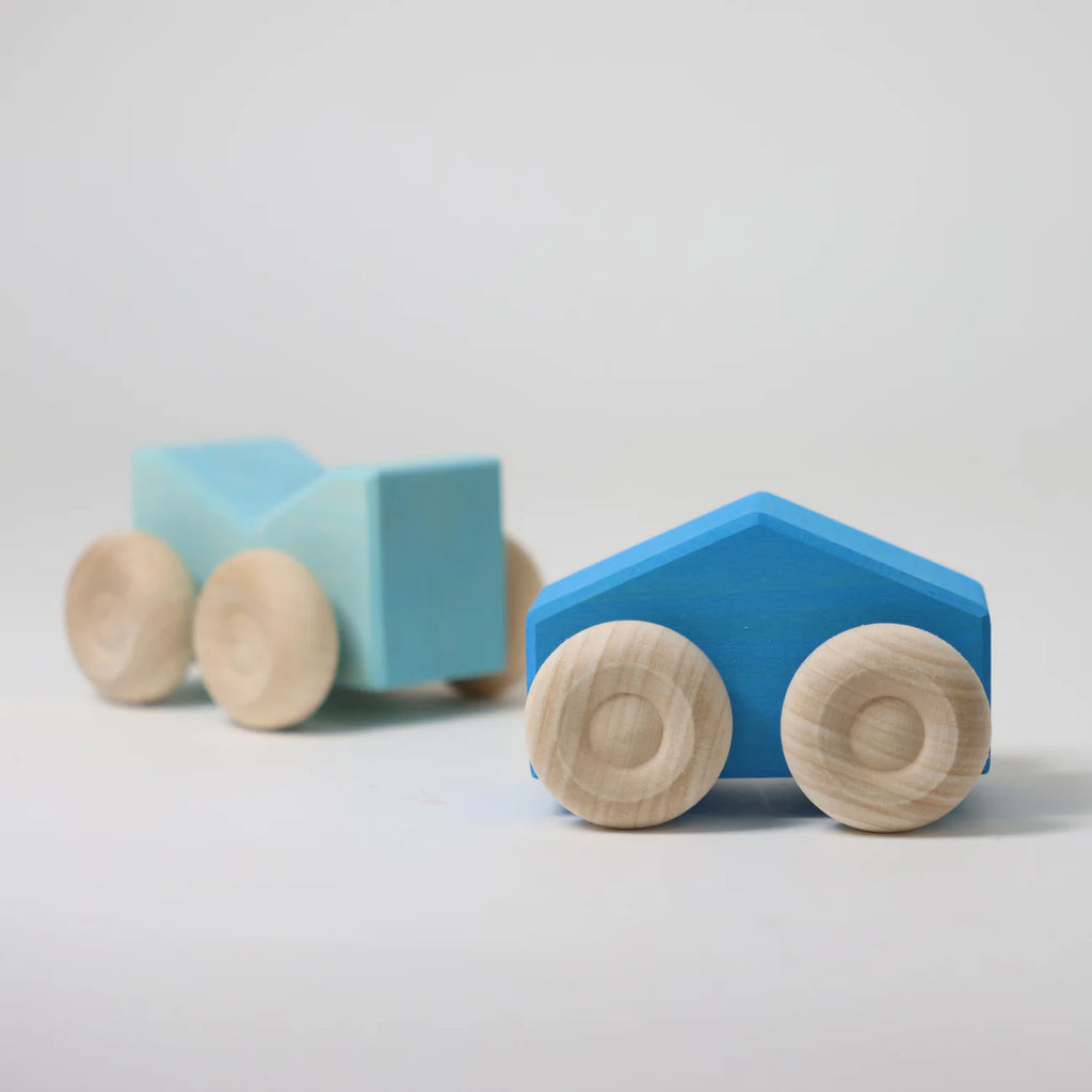 Two blue wooden toy cars with round wooden wheels on a light gray background