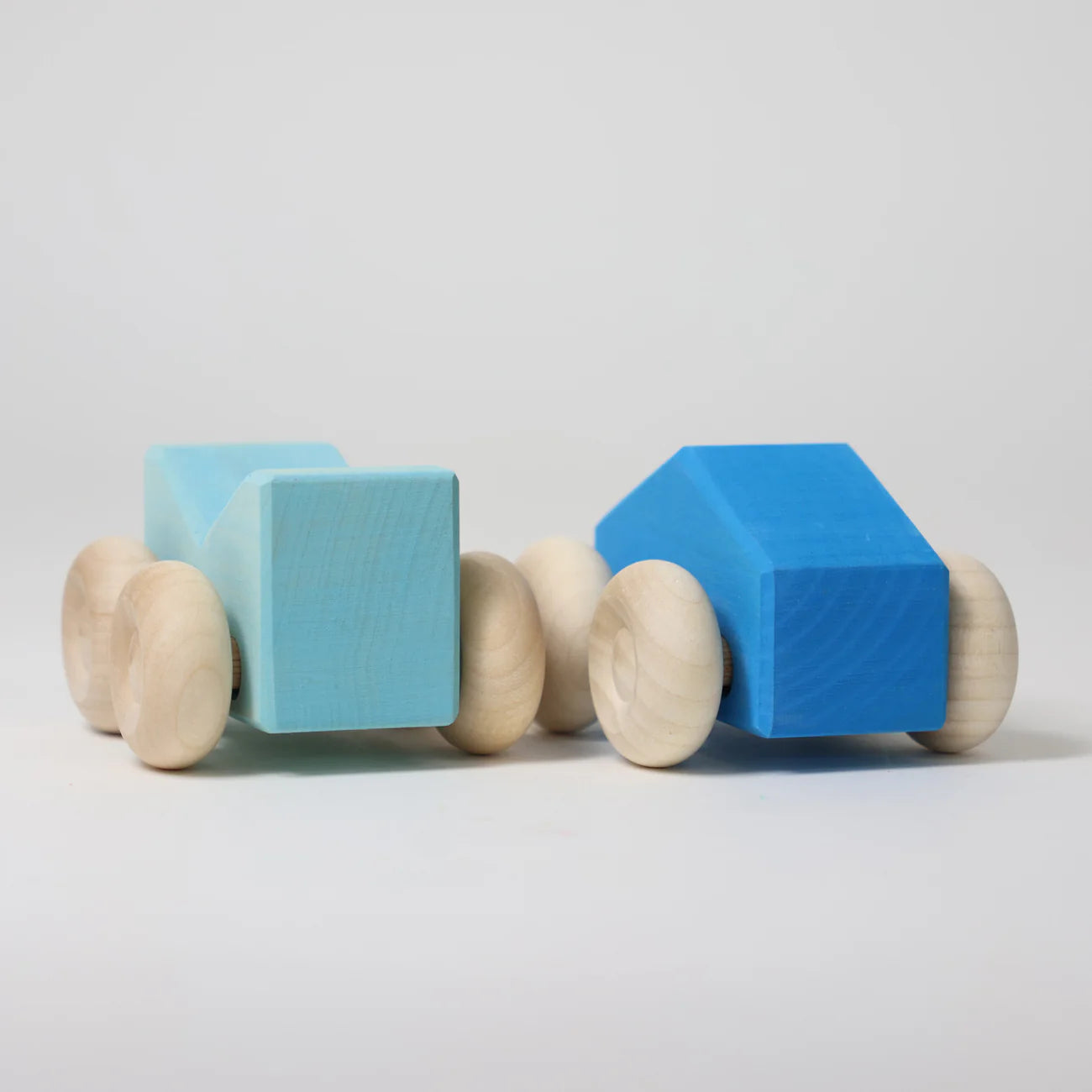 Two blue foam blocks with wooden wheels on a light gray background