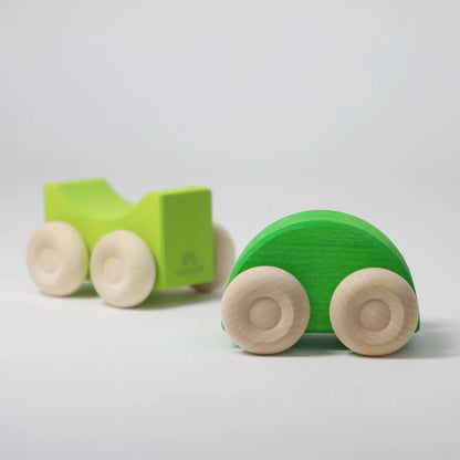 Two green wooden toy cars on a light gray background