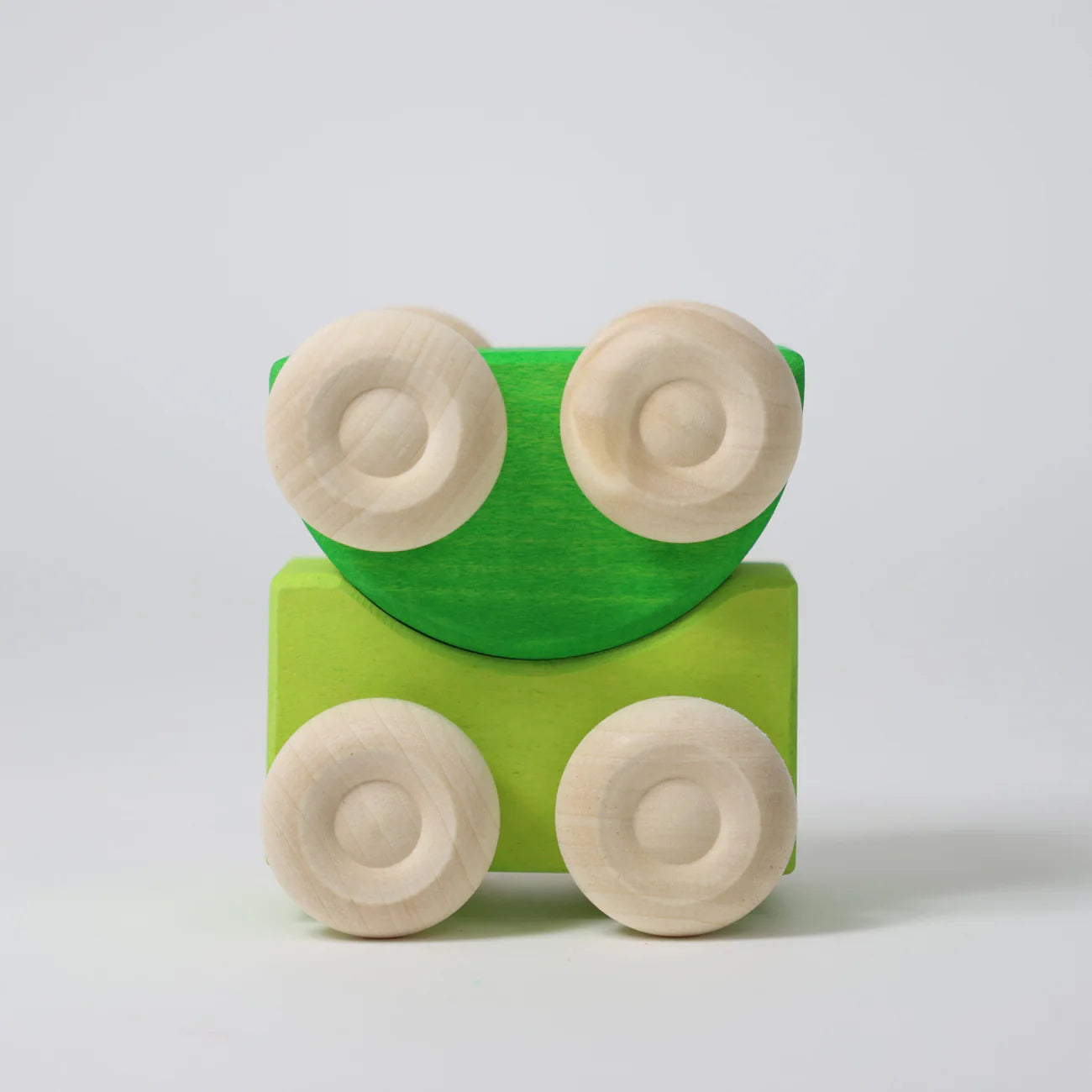 Green wooden block with four beige wheels on a light gray background
