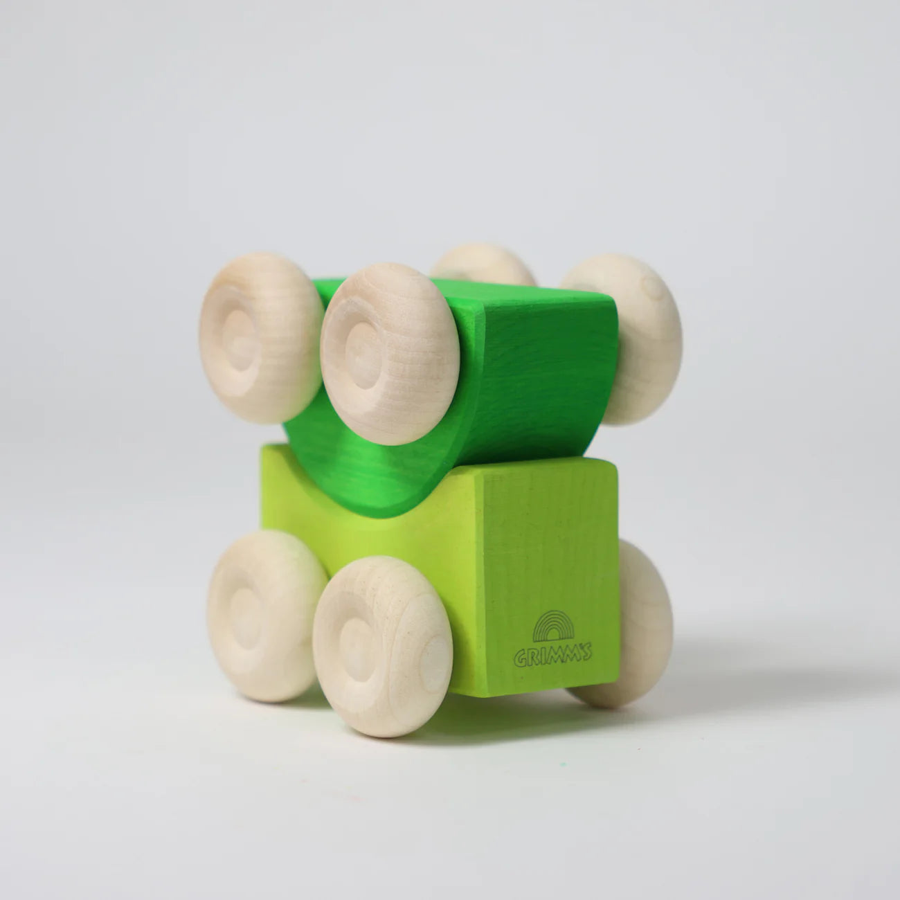 Green and beige toy block with wheels on a light gray background