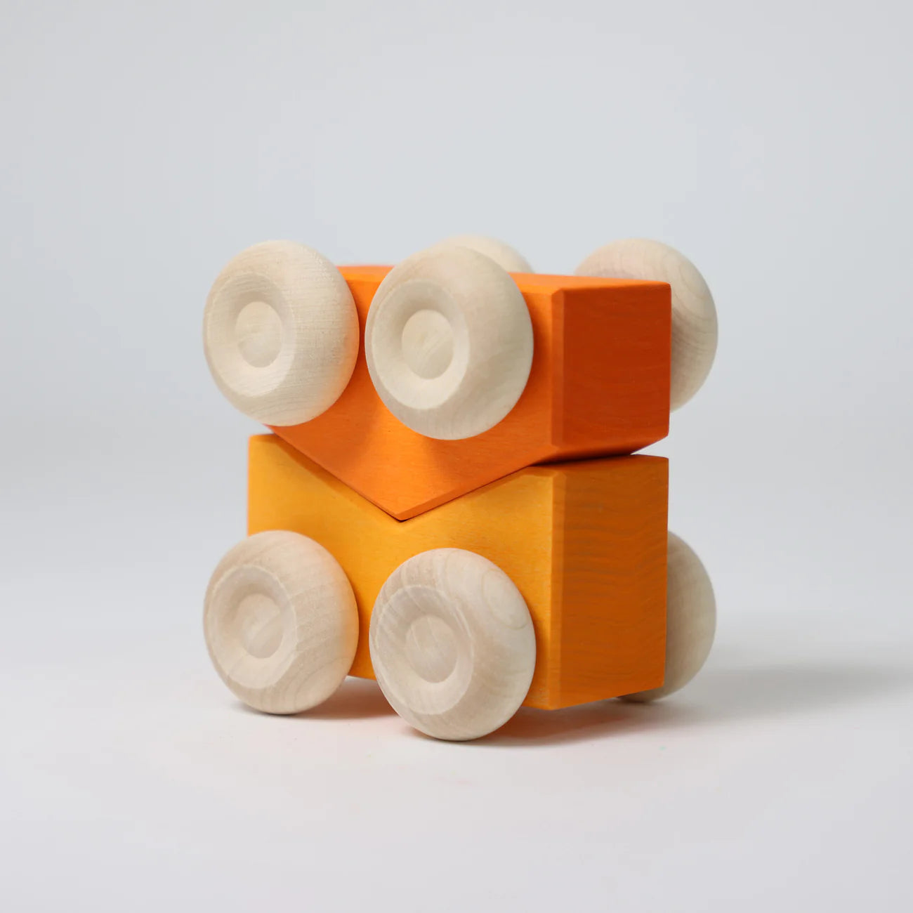 Wooden toy blocks with orange square bodies and beige circular ends on a light gray background