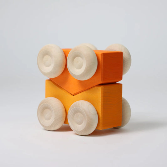 Wooden toy blocks with orange square bodies and beige circular ends on a light gray background