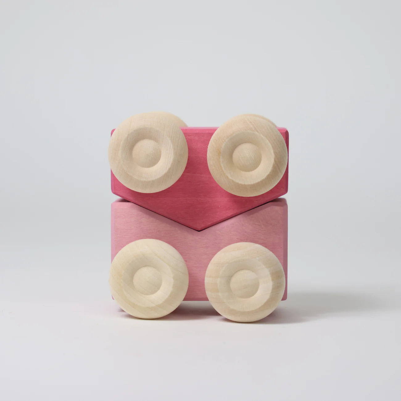 Pink toy block with beige circular pieces on a light gray background