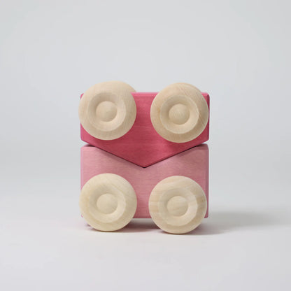 Pink toy block with beige circular pieces on a light gray background