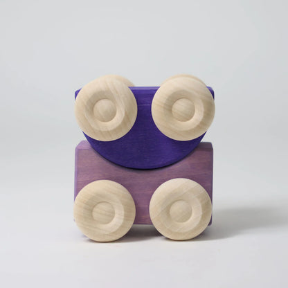 Wooden toy train with purple car and beige wheels on a light gray background