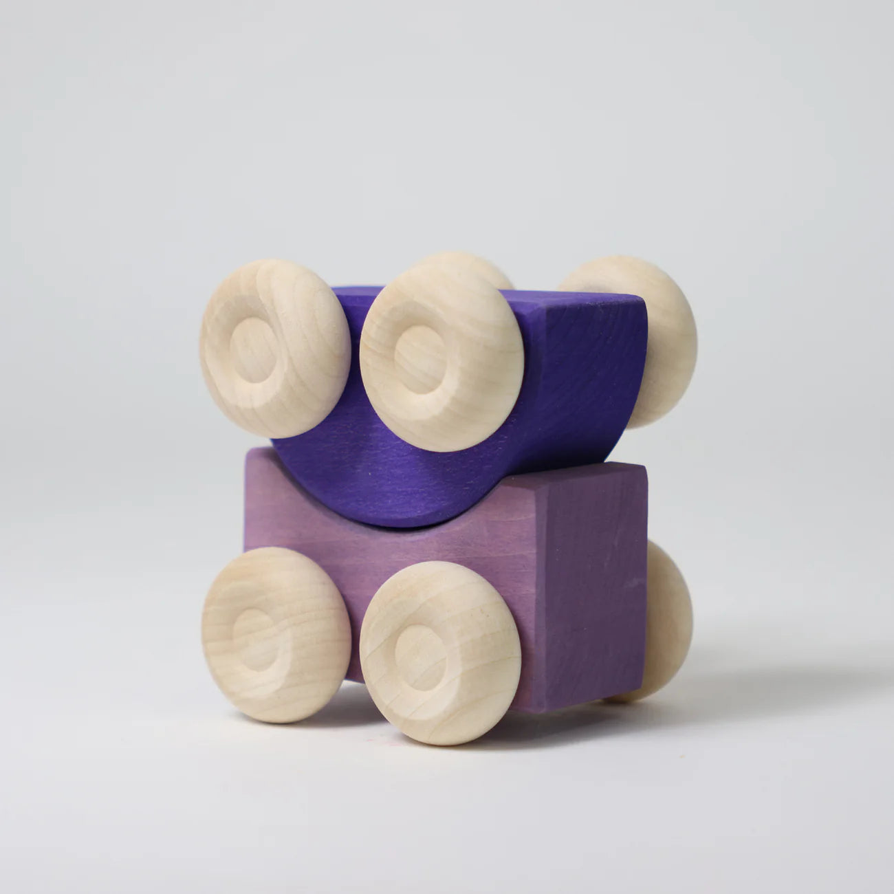 Purple wooden block with four beige wheels on a light gray background