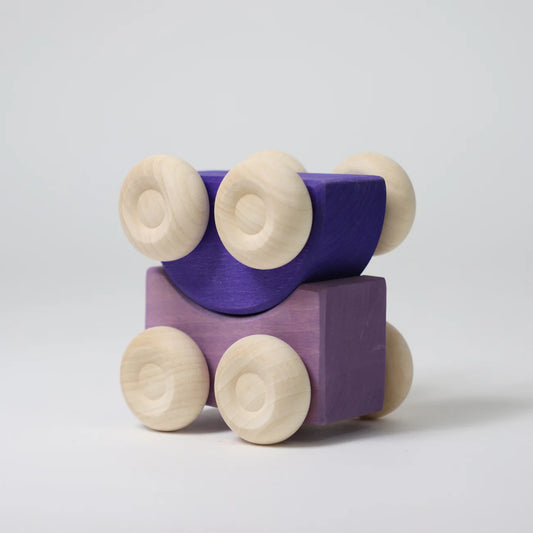 Purple wooden block with four beige wheels on a light gray background