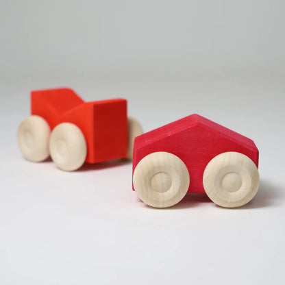 Two red wooden toy cars with beige wheels on a light gray background