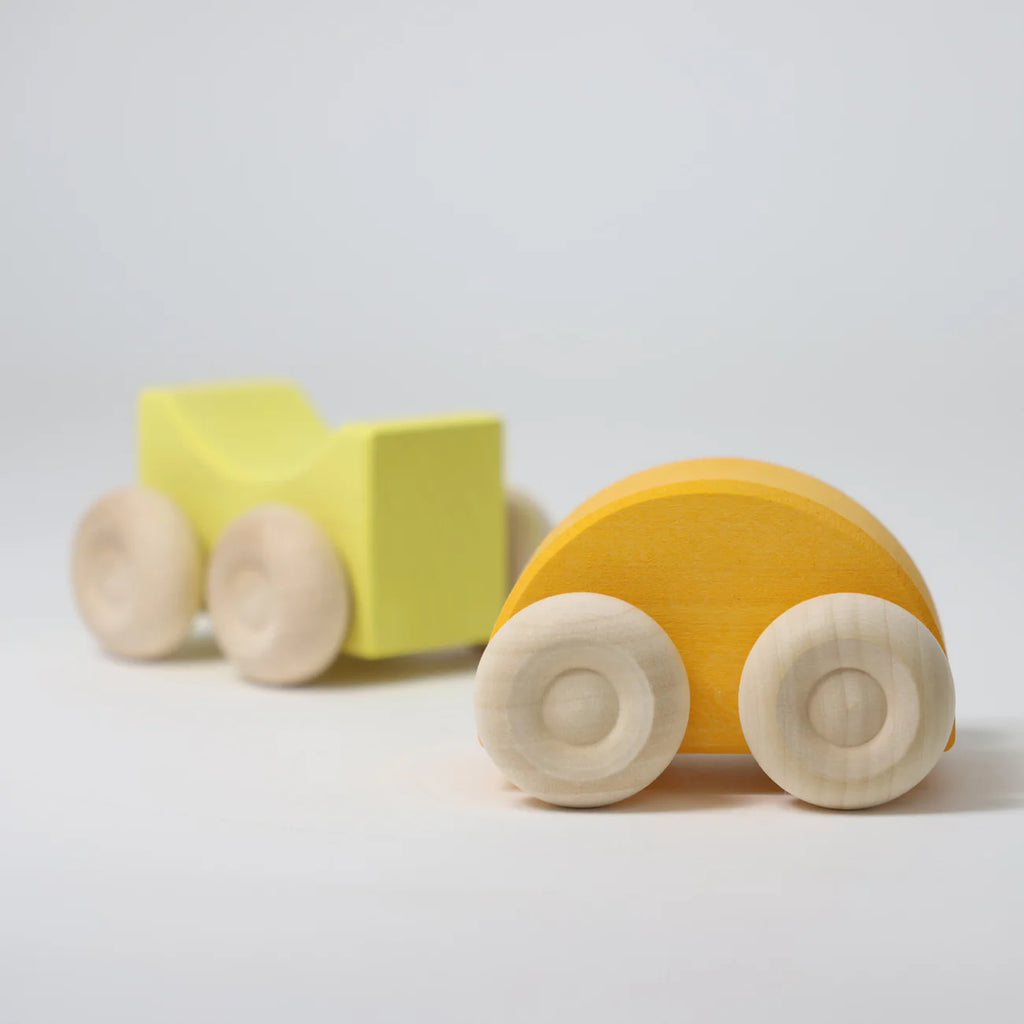 Wooden toy truck with a yellow body and light brown wheels on a light gray background