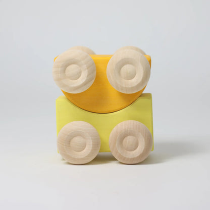 Yellow toy car with wooden wheels on a light gray background