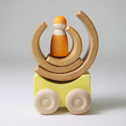 Wooden toy with a small figure on top and wheels at the bottom on a light gray background