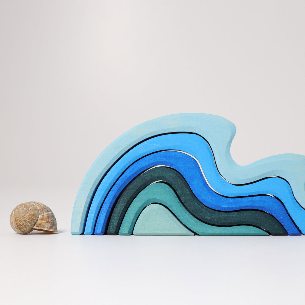 Stack of blue and green wooden toys with a shell on a light gray background