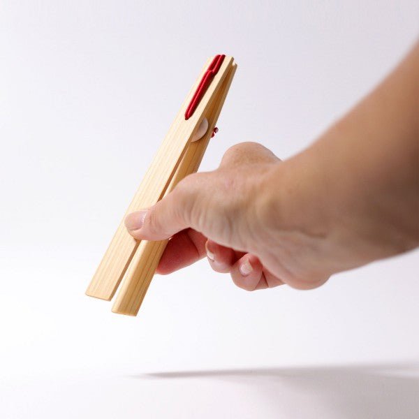 Hand holding a wooden tool with red accents on a white background