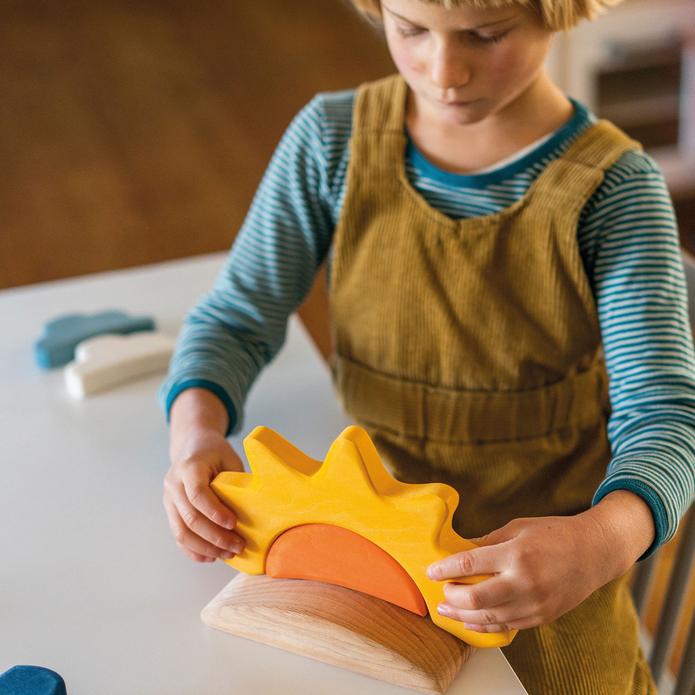 Child playing with a wooden toy sun on a table