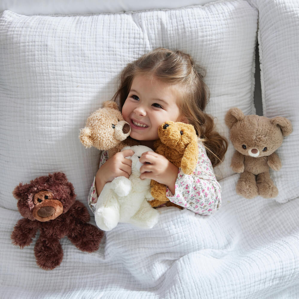 Child with teddy bears on a white bed