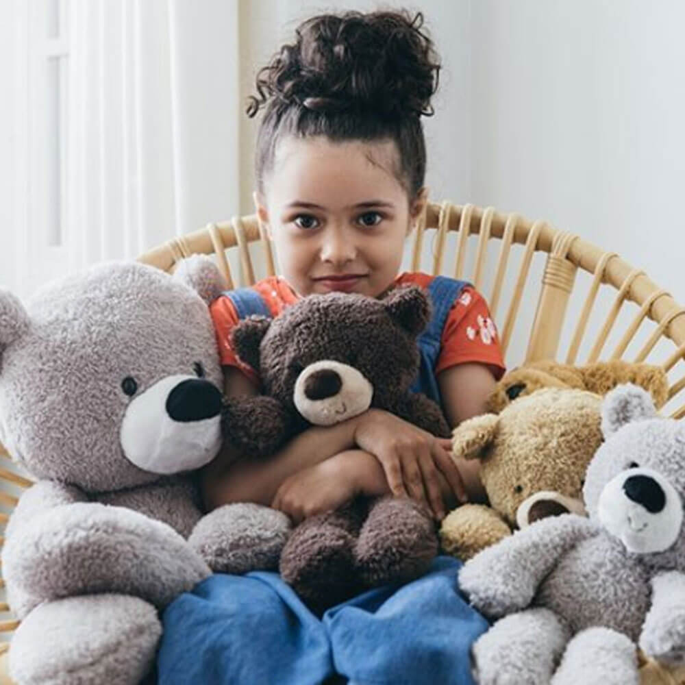 Child sitting in a chair surrounded by teddy bears