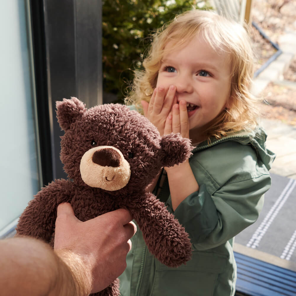 Child holding a brown teddy bear with a blurred background