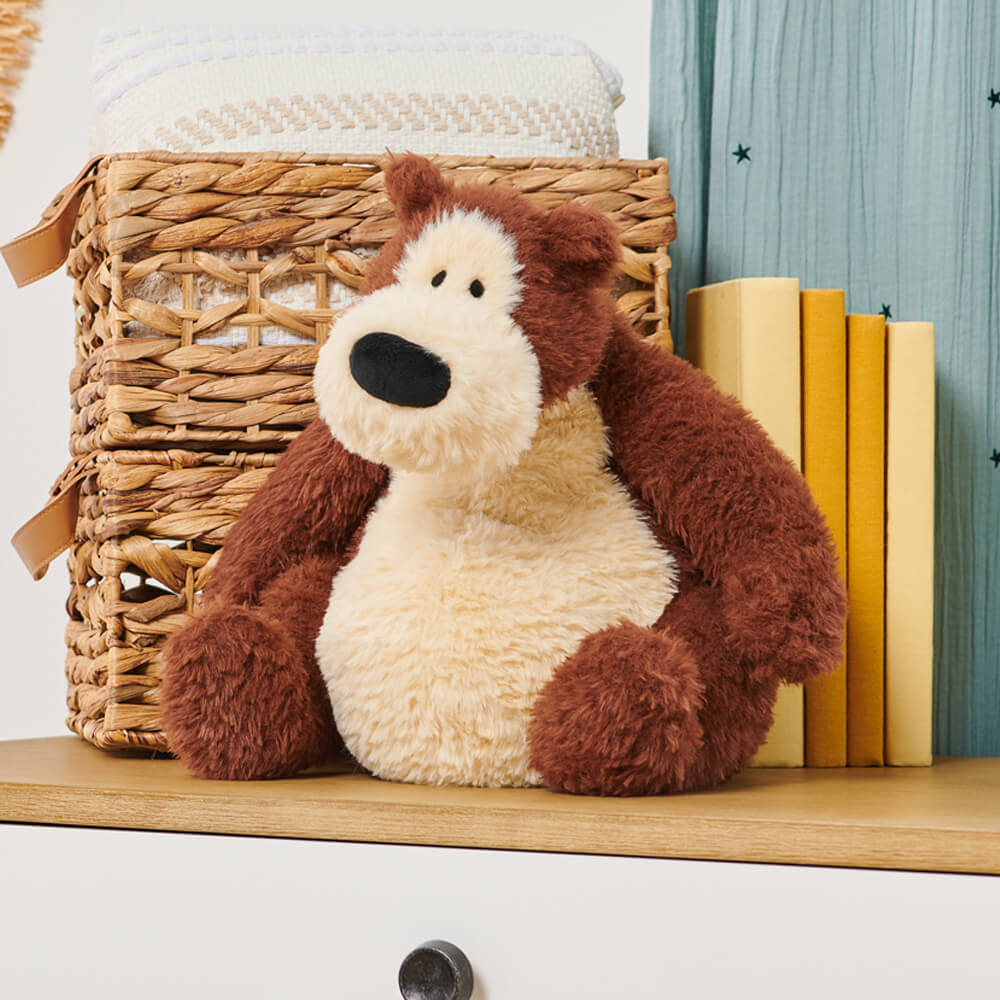 Plush teddy bear on a wooden shelf with books and a woven basket in the background
