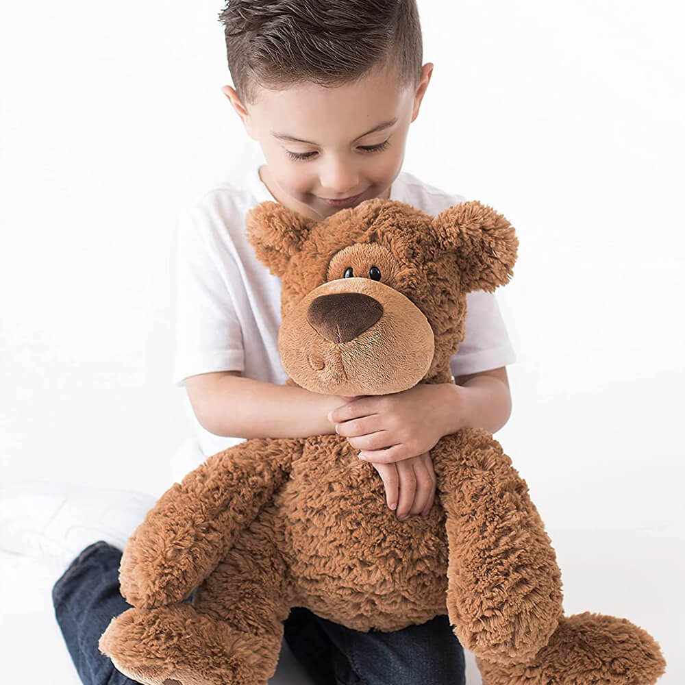Child holding a large brown teddy bear against a white background