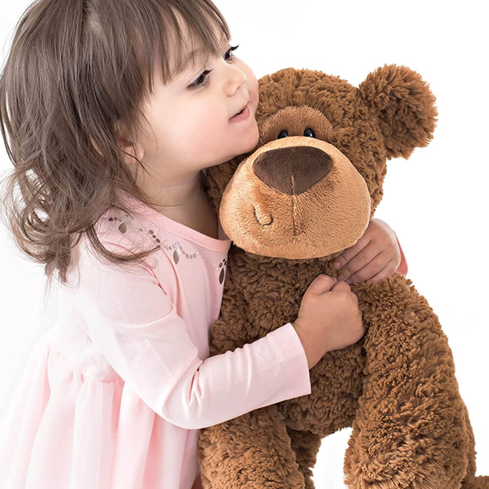 Child hugging a large brown teddy bear on a white background
