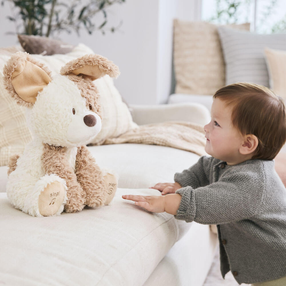 Child interacting with a plush toy on a couch in a cozy living room.