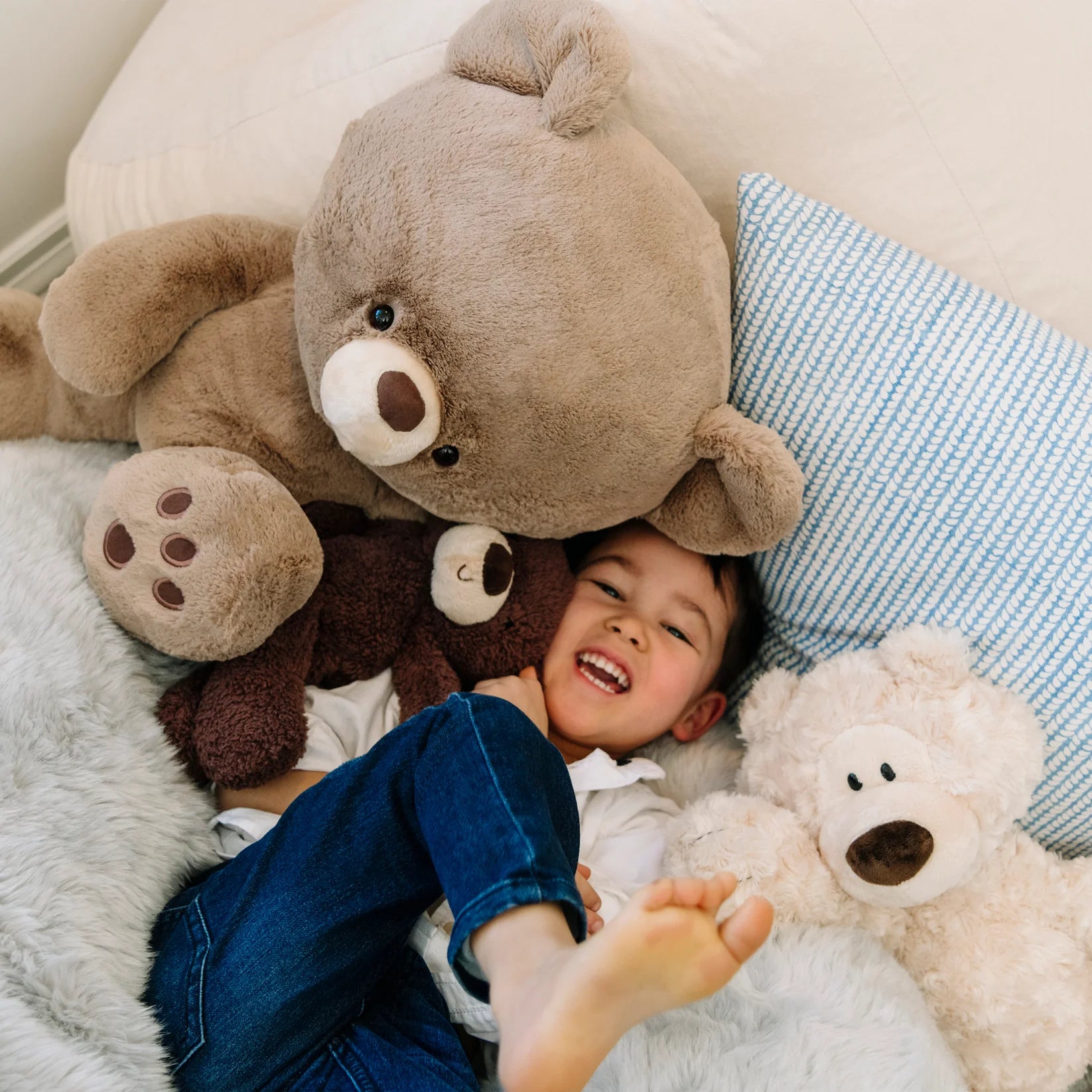 Child lying on a bed with teddy bears and pillows