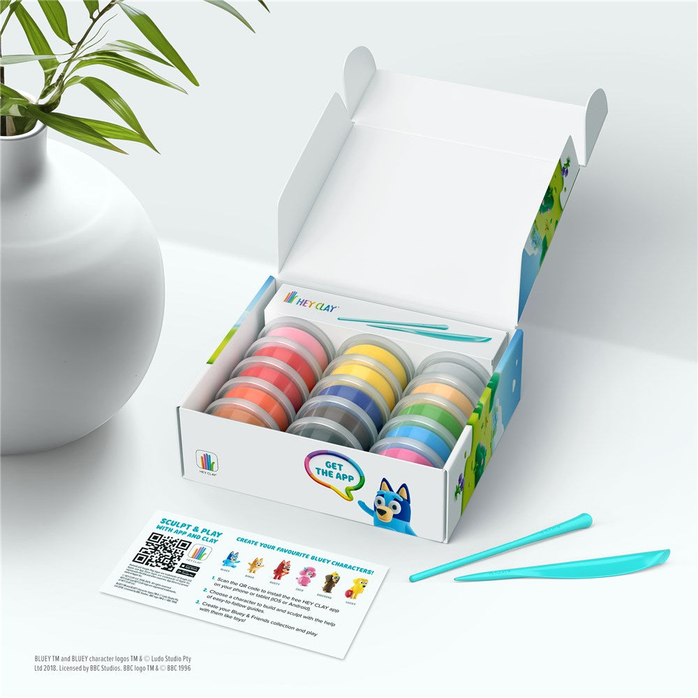 Box of colorful play dough with a plant and card on a white surface