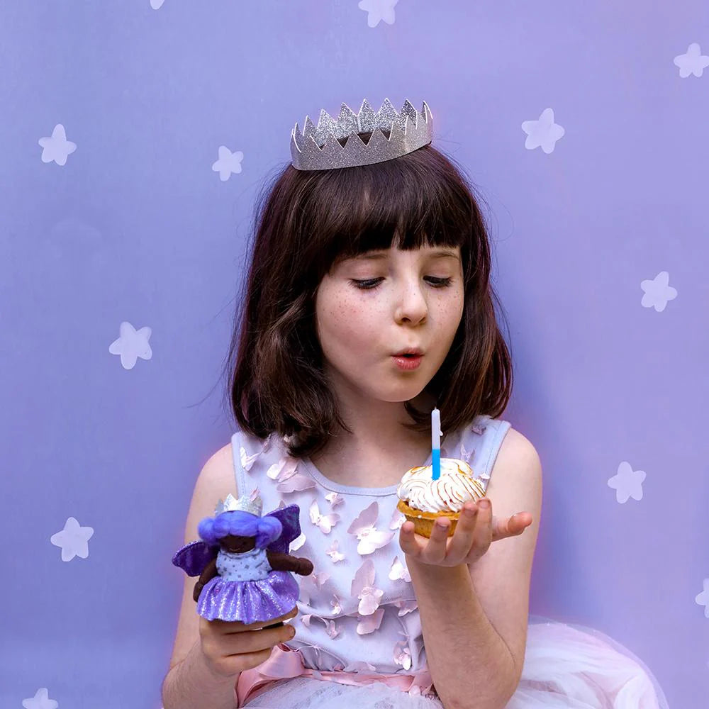 Child holding purple fairy and cupcake on a purple background