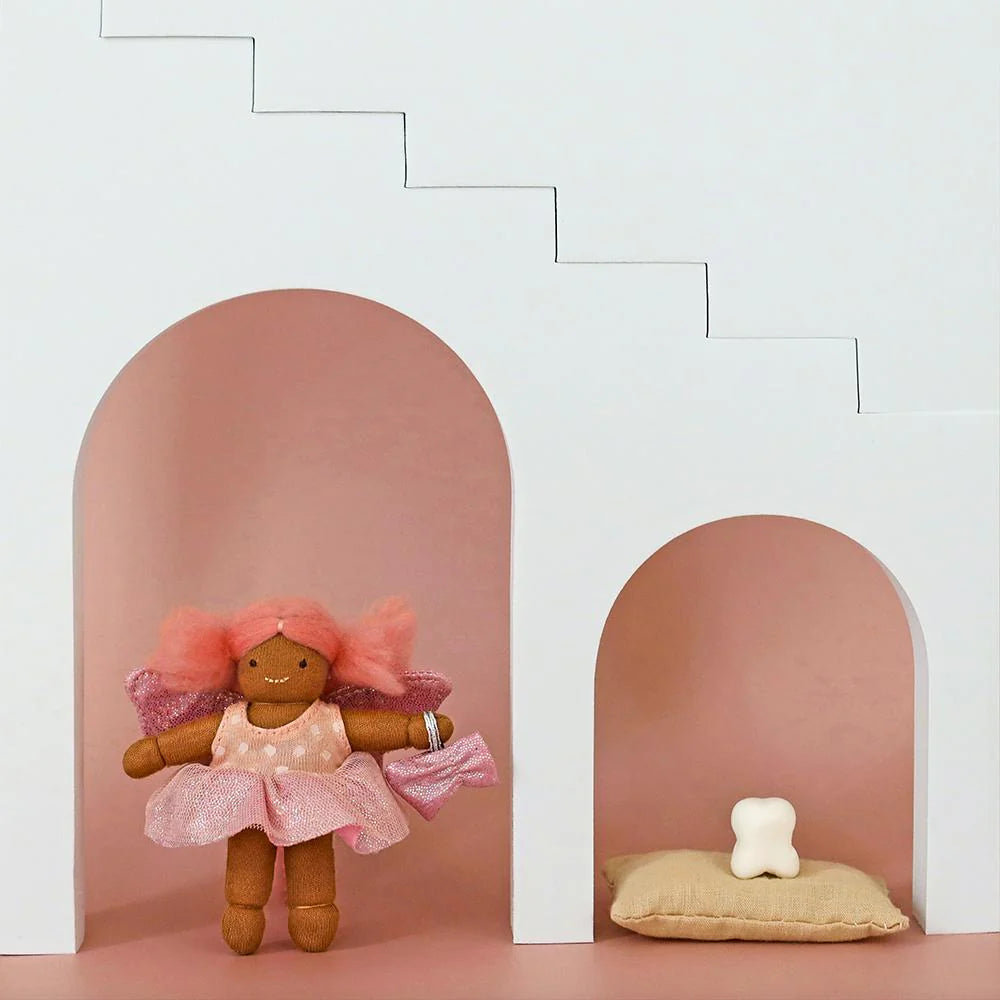 Small doll with pink hair and dress standing between two pink arches on a light pink floor.