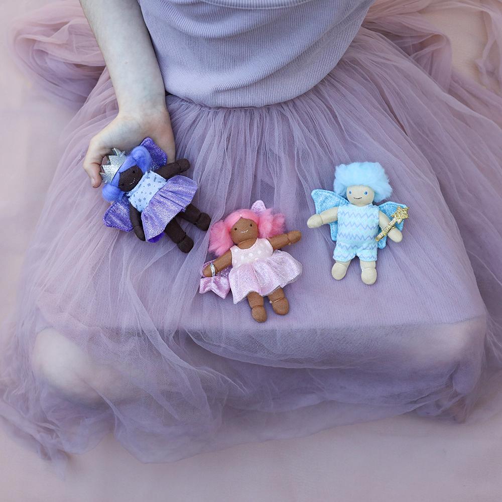 Three small plush toys held by a person wearing a tulle skirt.