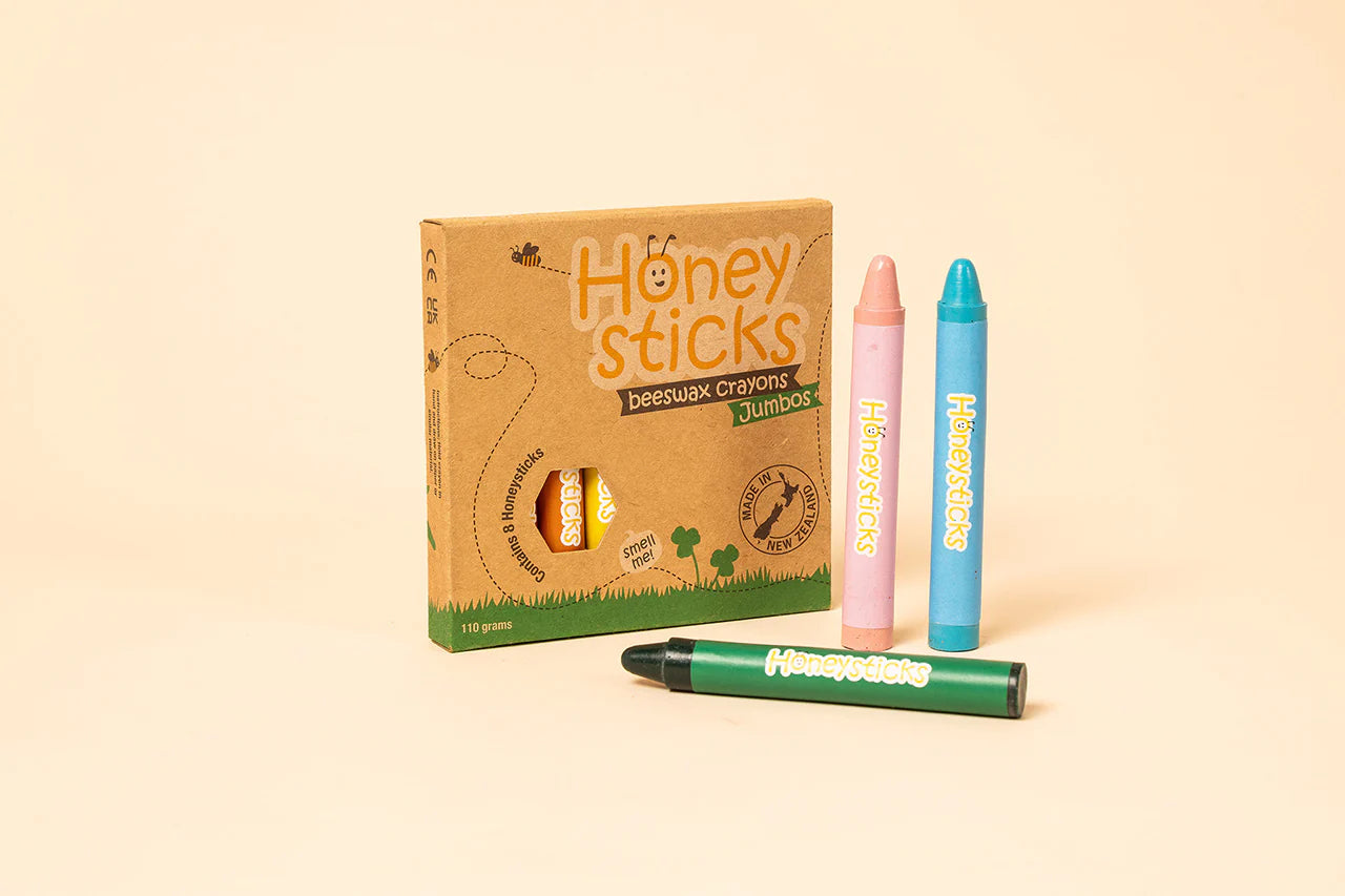Honey Sticks crayons with packaging on a beige background