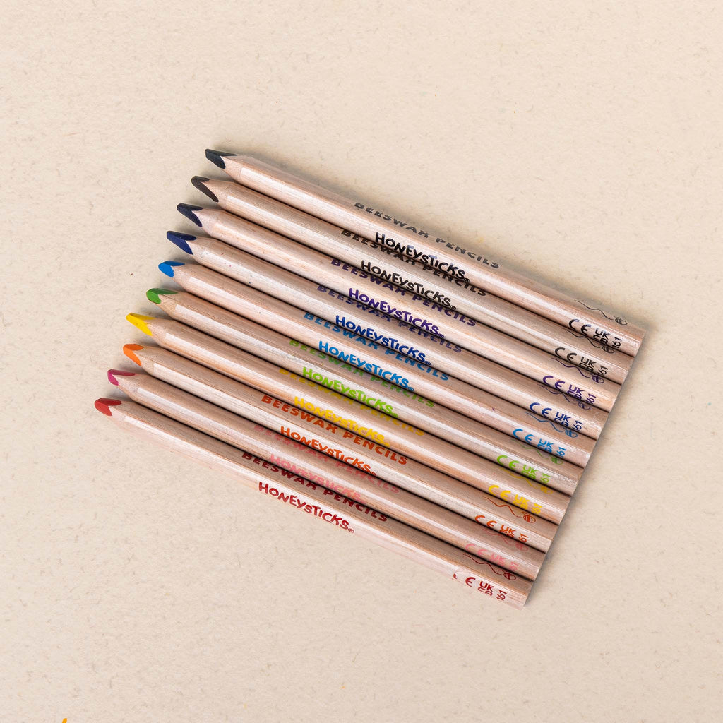 Set of colored pencils with visible brand names on a beige background