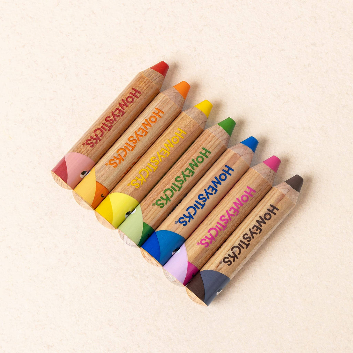 Set of colorful pencils with 'HONESTSTICKS' branding on a beige background